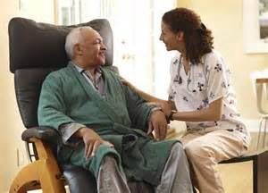 Elderly man in chair and women helping